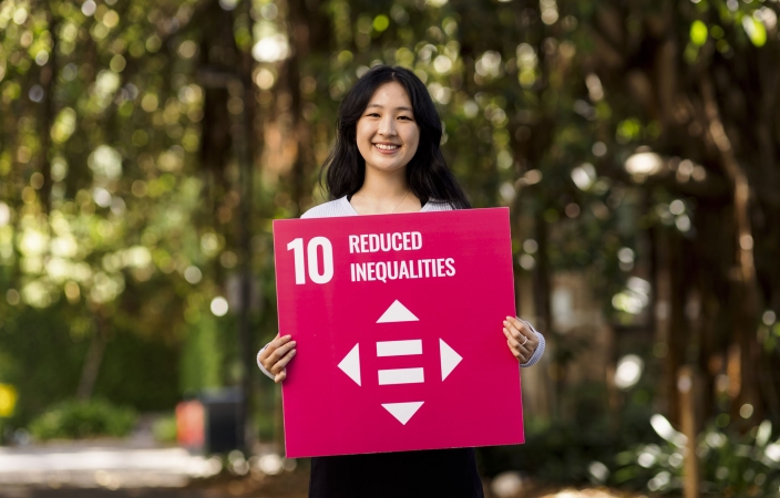 Angela holds up a sign advocating for the UN SDGs