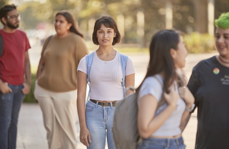Student walking amongst crowd looking directly at camera