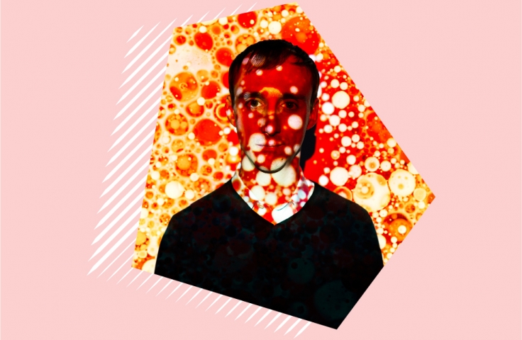A man standing in-front of a wall with a projection of red and orange bubbles over his face