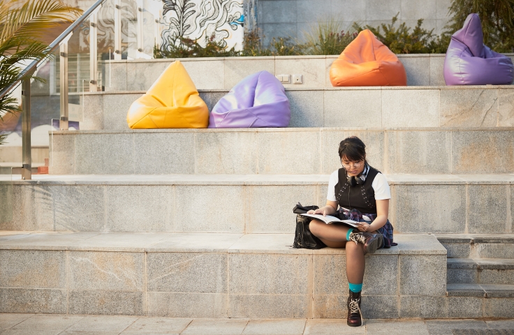 Woman on reading on steps with multi-coloured bean bags in background