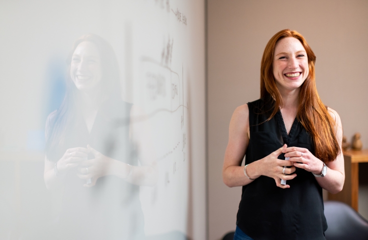 A woman smiling in front of a whiteboard